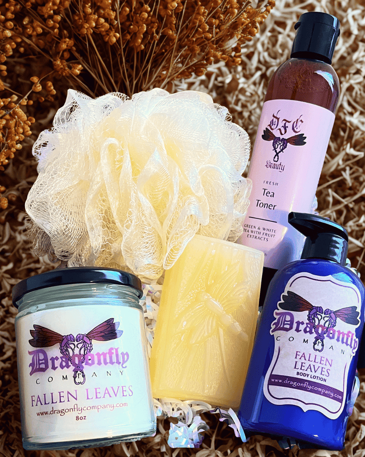Set of Dragonfly Company products including a candle, soap, lotion and tea toner on a textured surface.