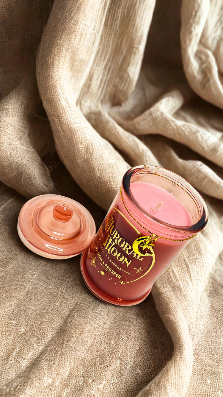 Pink scented candle with a decorative label on beige fabric