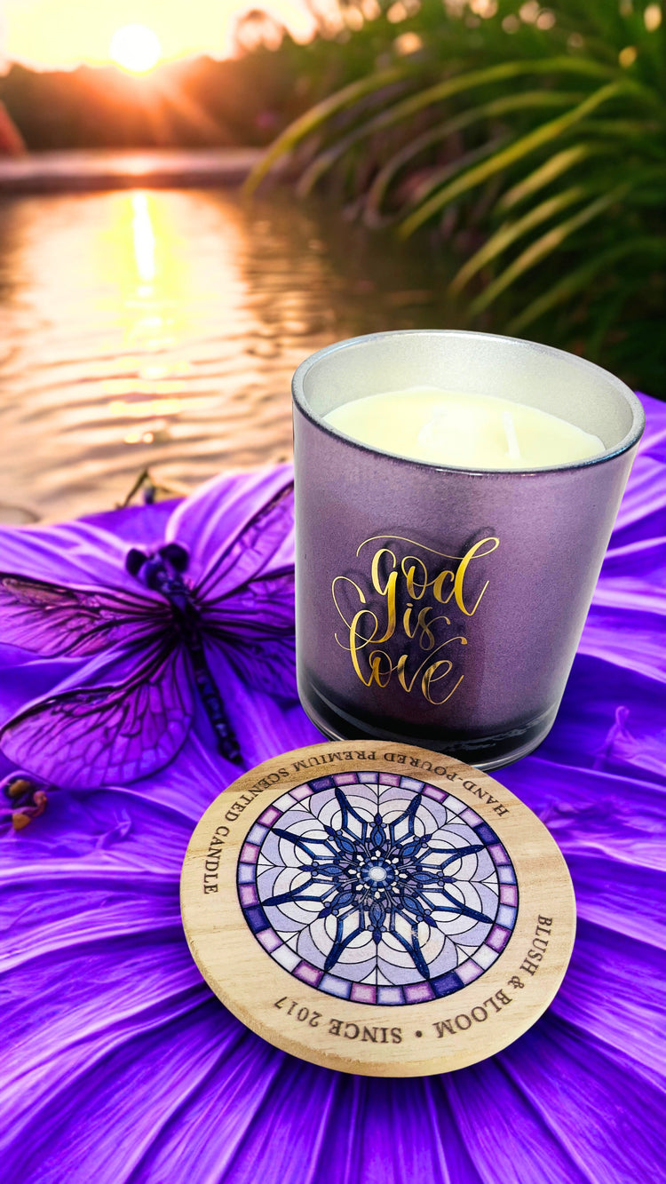 Candle with 'God is Love' text on a purple flower with sunset background