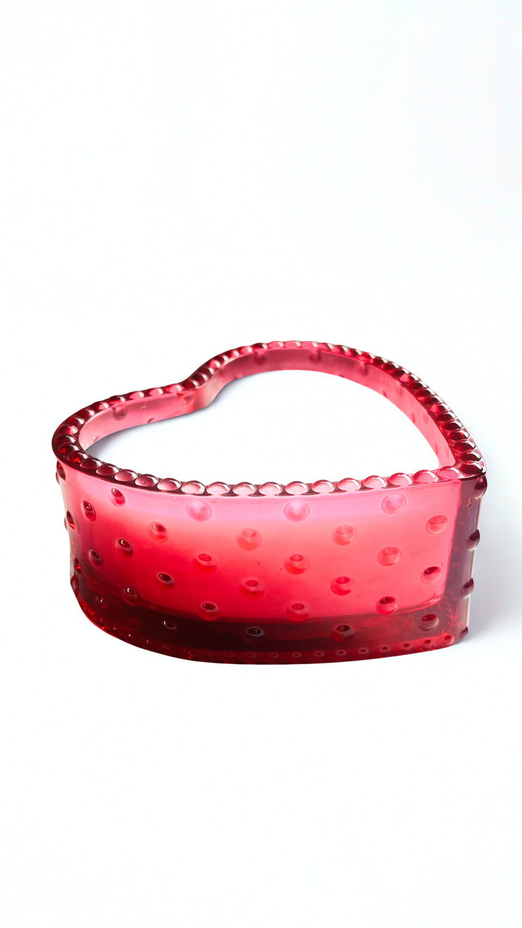 Red glass bowl candle with textured surface on a white background
