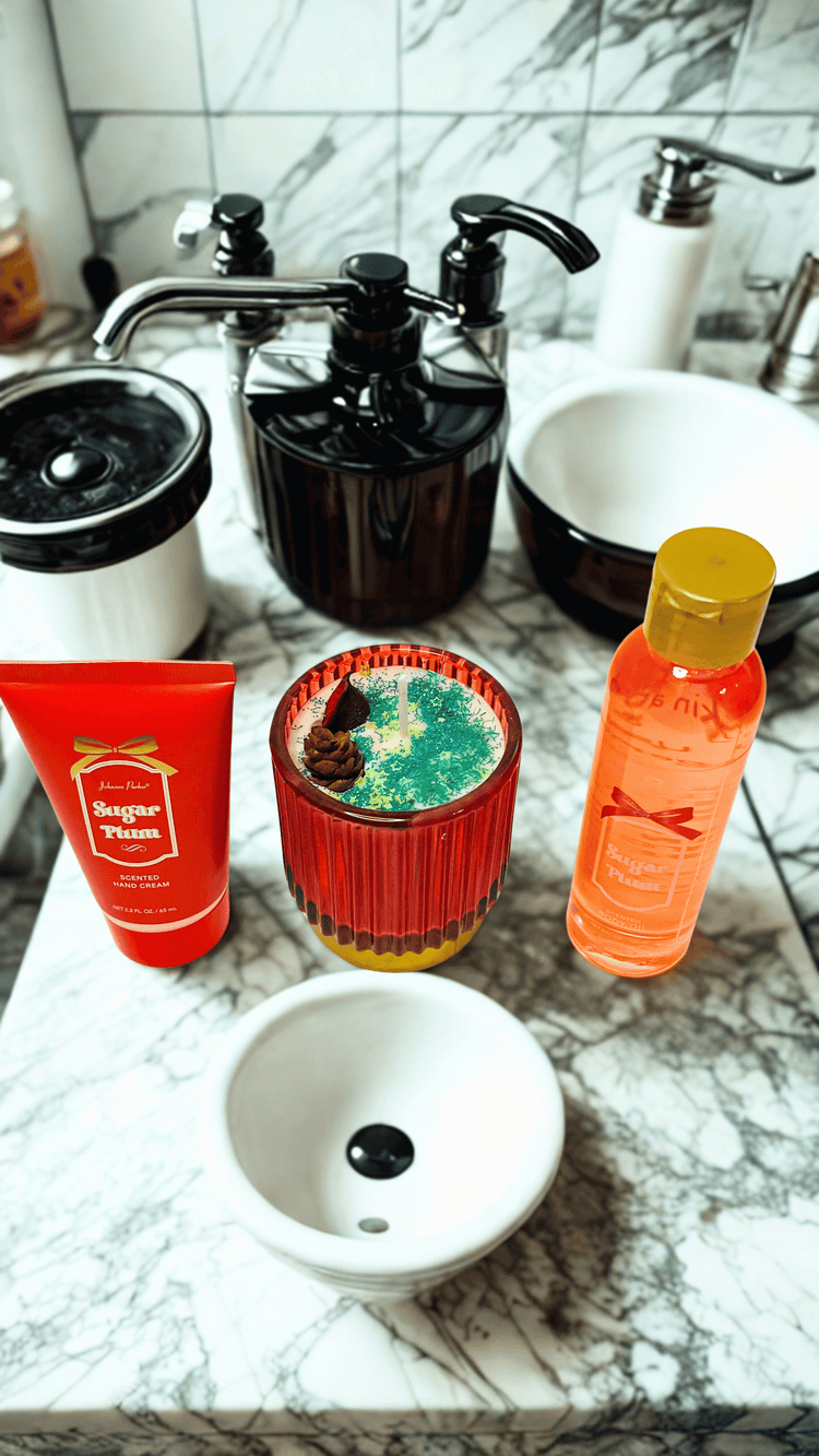 Cosmetic products and candle on a marble countertop with a sink in the background