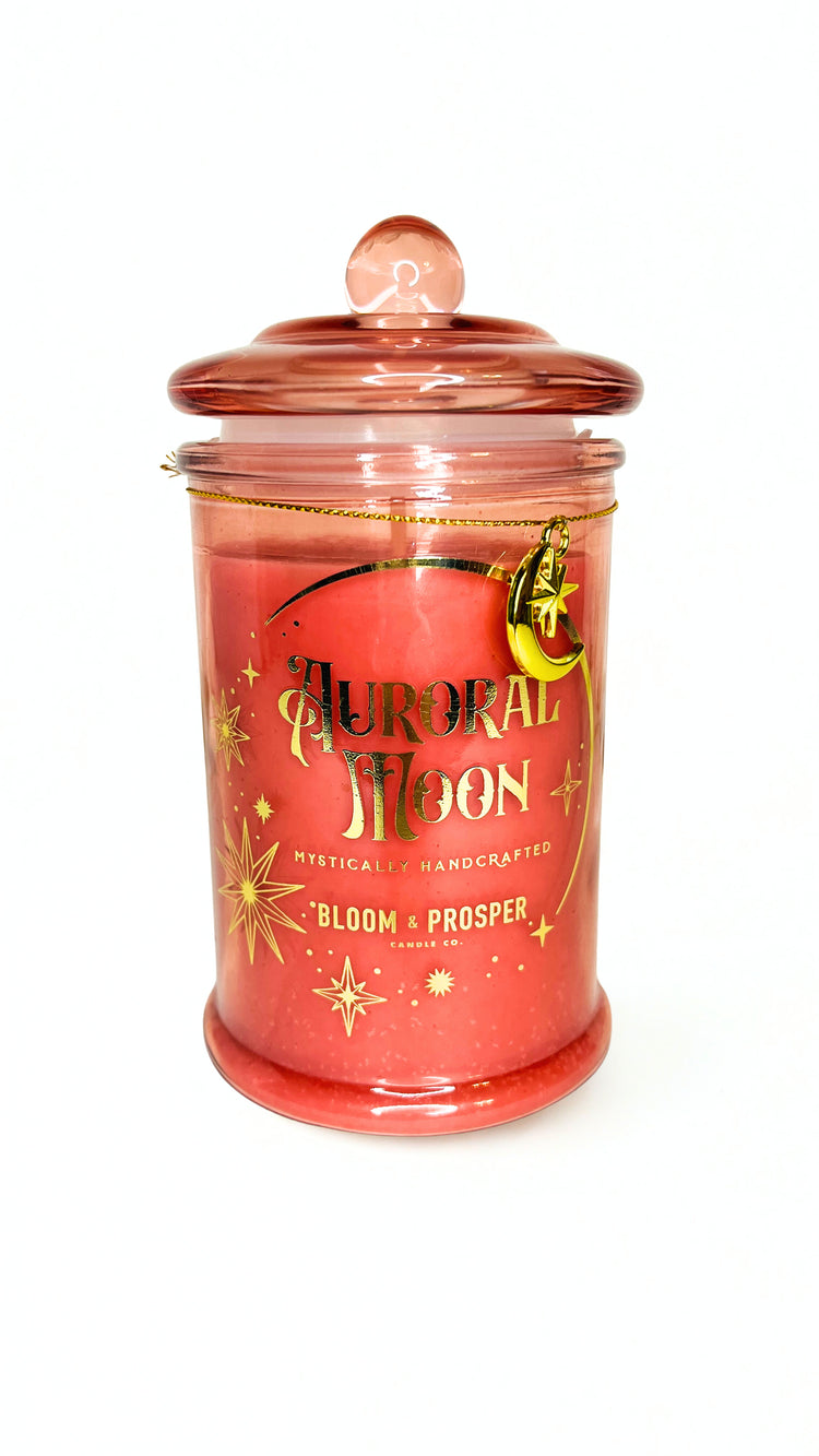 Candle jar with decorative label and moon bracelet on a white background