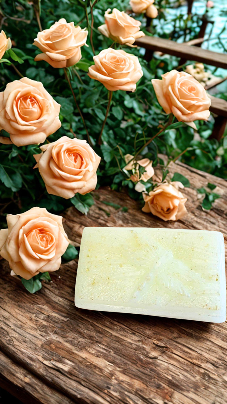Bar of Clarity soap on a wooden surface with peach roses in the background