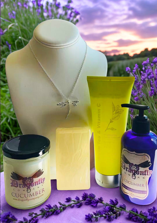 A curated collection of Dragonfly Cucumber skincare and wellness products arranged on a purple surface with lavender sprigs and a blurred lavender field sunset background.
