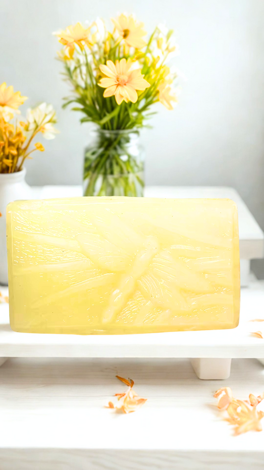 Dragonfly Fallen Leaves soap on a white surface with yellow flowers in the background