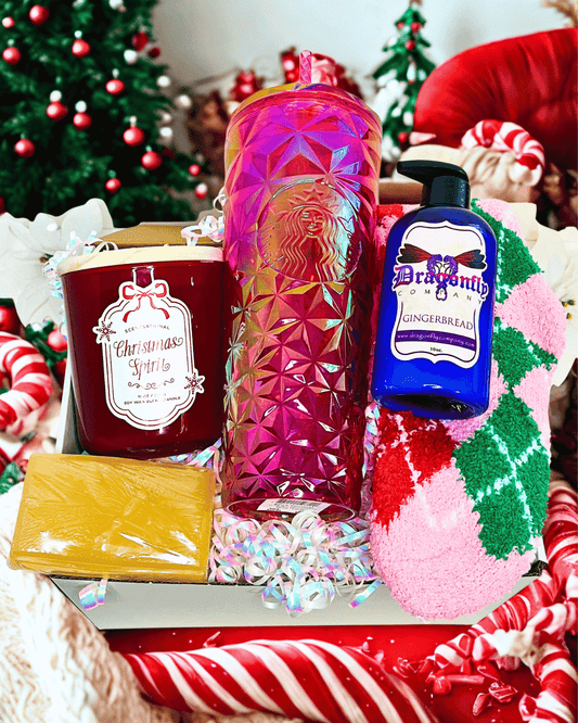 Gift box with Christmas-themed items including a candle, Starbucks bottle, soap, lotion socks against a festive background.