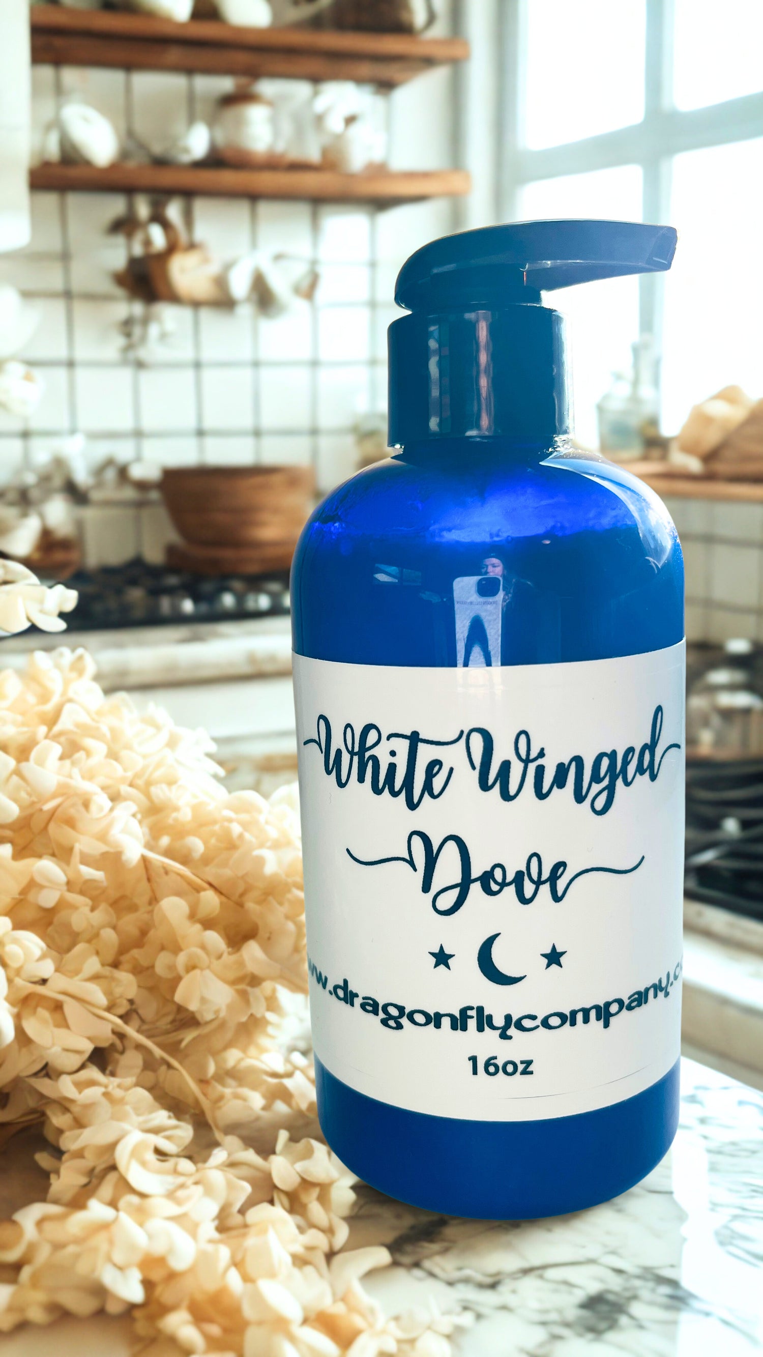 Bottle of 'White Winged Dove' lotion on a kitchen counter with decorative elements.
