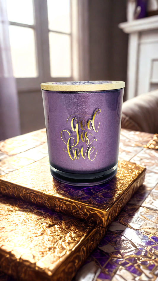 Purple candle with 'God is Love' text on a decorative surface