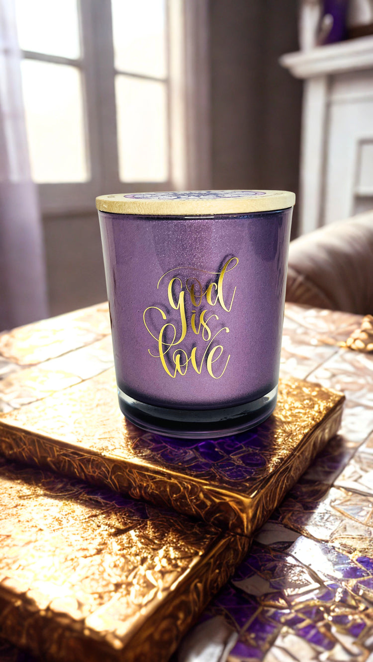 Purple candle with 'God is Love' text on a decorative surface