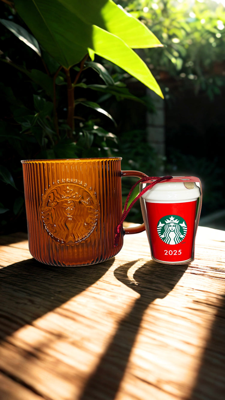  Starbucks mug and a ornament  on a wooden surface with greenery in the background