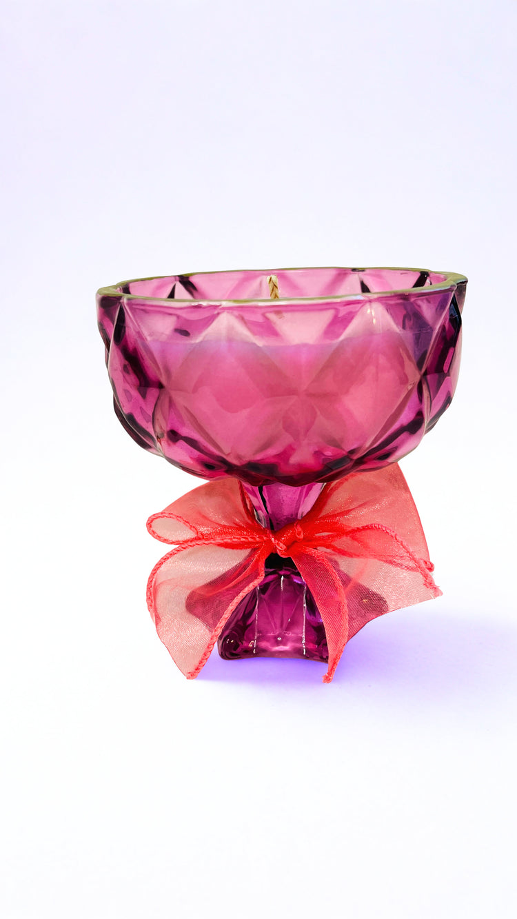 Pink glass goblet candle with bow on a white background 