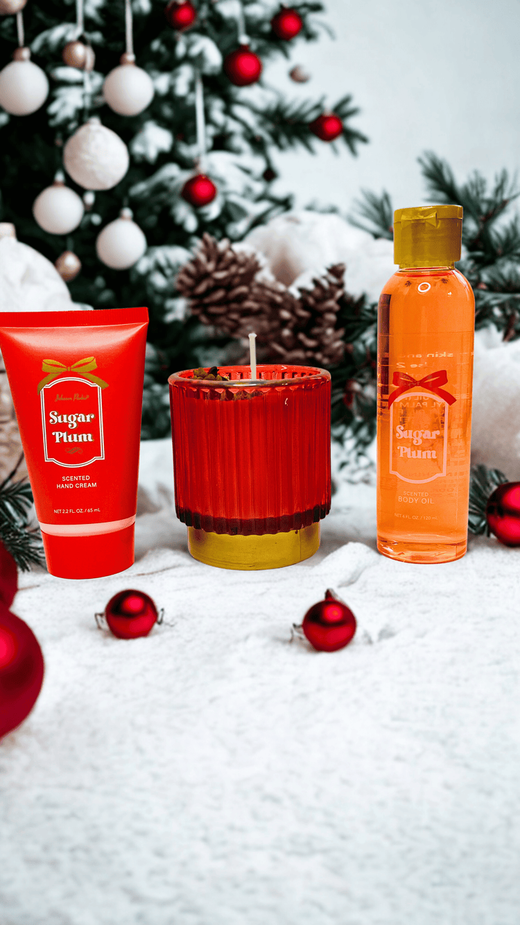 Holiday-themed skincare products and candle with a Christmas tree in the background