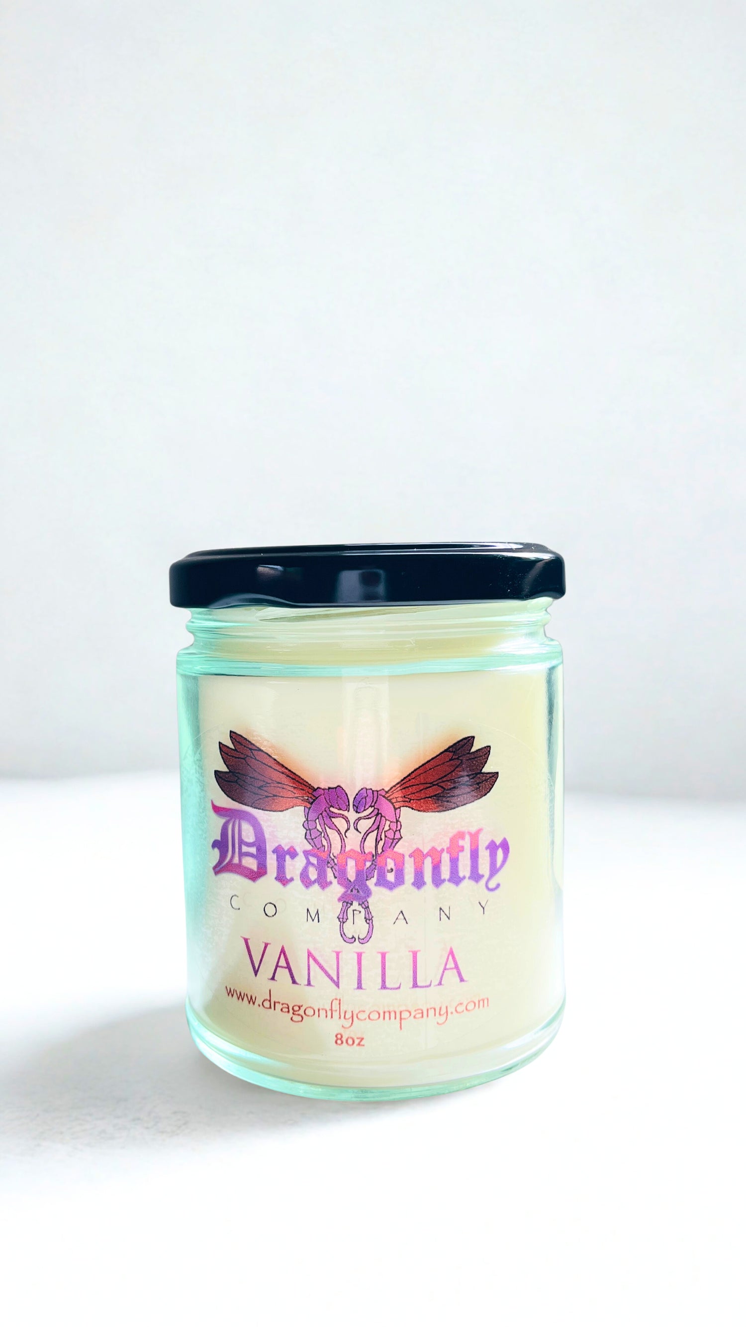 Vanilla scented candle in a glass jar with a black lid on a white background