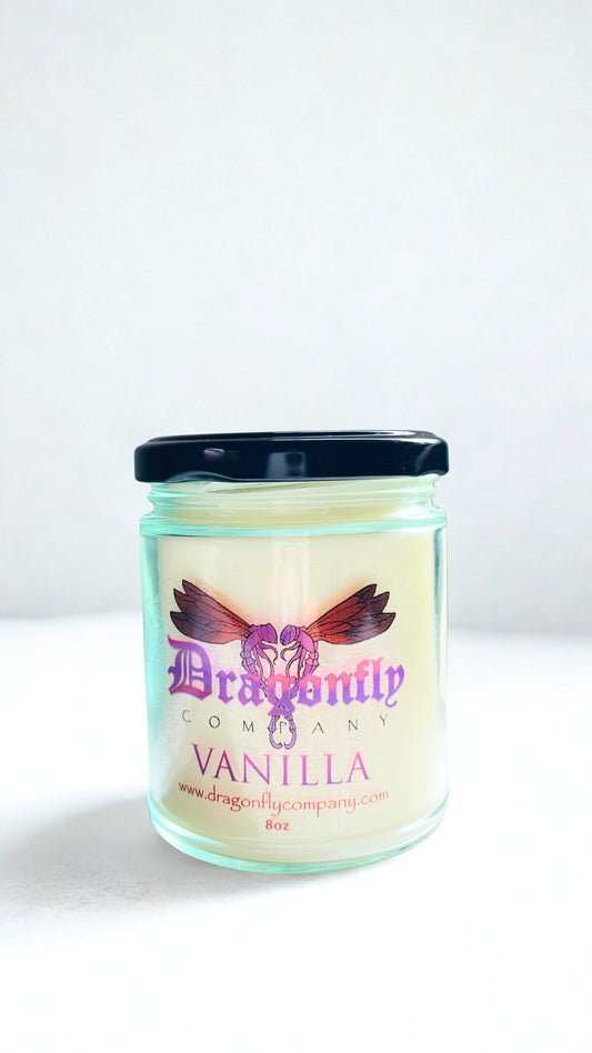 Vanilla scented candle in a glass jar with a black lid on a white background