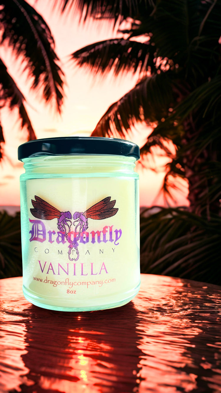 Vanilla scented candle with 'Dragonfly Company' branding against a palm tree background